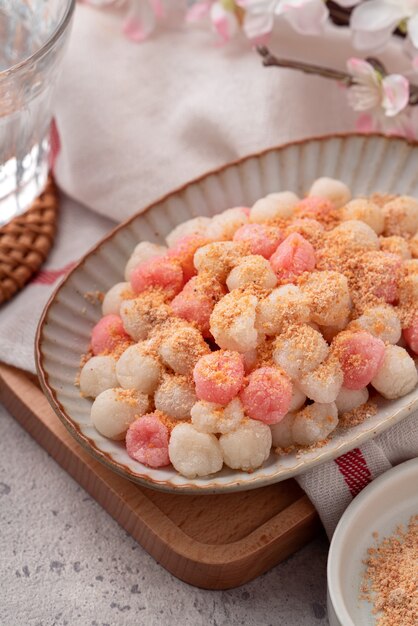 Gros plan de tangyuan rouge et blanc frit (tang yuan, boulettes de boulettes de riz gluant) avec de la poudre d'arachide sur fond de table gris pour la nourriture du festival du solstice d'hiver.