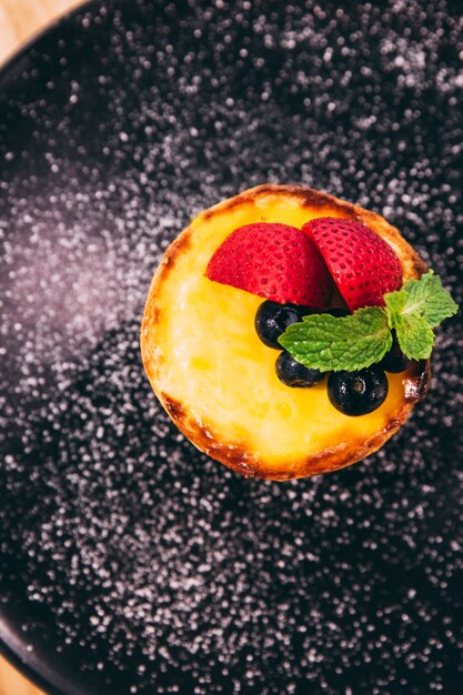 Gros plan La tarte au fromage avec des tranches de fraises et de mûres avec du sucre glace.