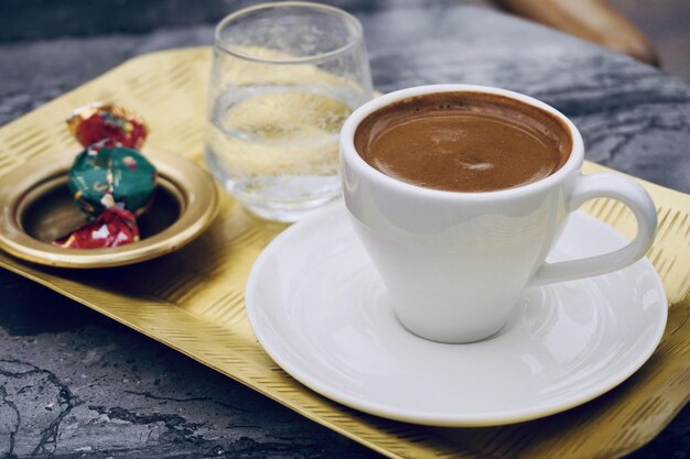 Gros plan d'une tasse de café avec des bonbons et un verre d'eau sur un plateau