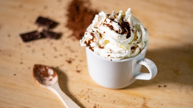 Gros plan d'une tasse de café avec de la poudre de cacao à la crème fouettée et de la cannelle