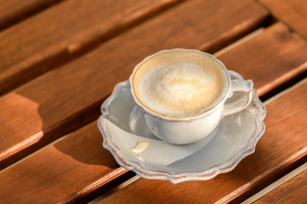 Gros plan d'une tasse de cappuccino sur une table d'été en bois au coucher du soleil, profitant du bon moment et du bon moment, vie lente et désintoxication numérique, santé mentale, temps pour moi, gratitude du jour et plaisirs simples