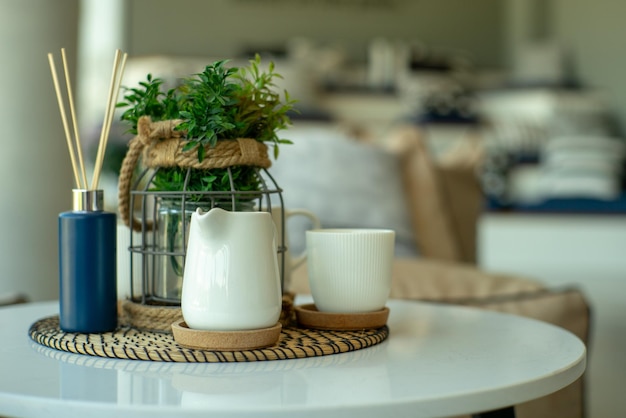 Un gros plan d'une tasse en céramique blanche et d'une cruche de thé et de café avec un fond bokeh