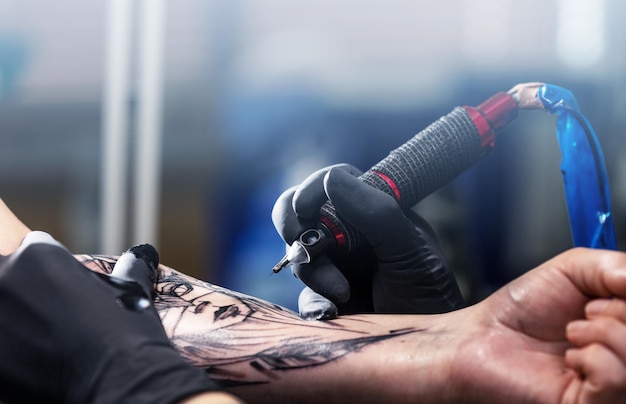 Photo gros plan d'un tatoueur tatoue un tatouage noir avec de la peinture tatouage remplissez un tatouage de circuit de tatouage
