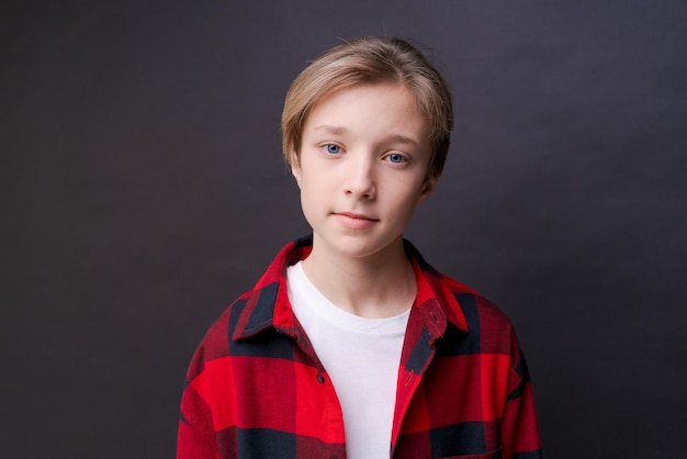 Gros plan sur la tête d'un jeune homme confiant et concentré en chemise à carreaux regardant un portrait de studio de caméra isolé sur fond de studio noir Un homme réfléchi du millénaire pose pour un album photo