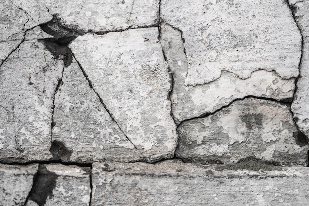 Gros plan de la texture du plâtre fissuré sur le mur de la vieille maison