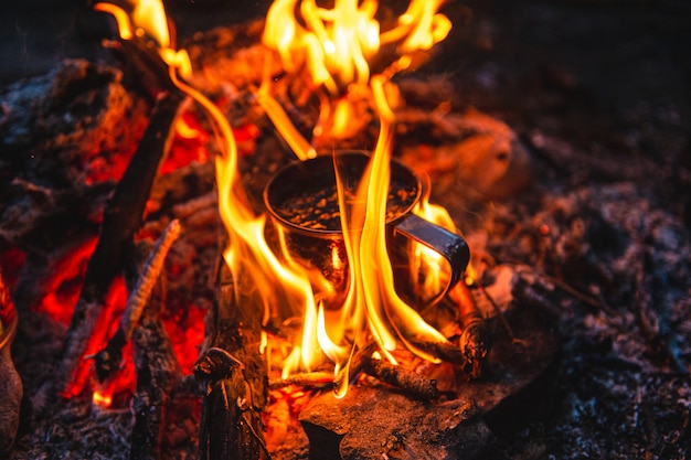 Gros plan de thé dans une tasse en métal se réchauffe dans un feu de joie