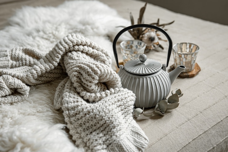 Photo gros plan sur une théière de style scandinave avec thé avec élément tricoté et détails de décoration.