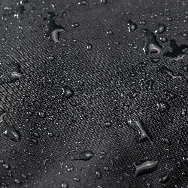 Gros plan en tissu hydrophobe imperméable gris foncé avec gouttes d'eau fond de mise au point sélective