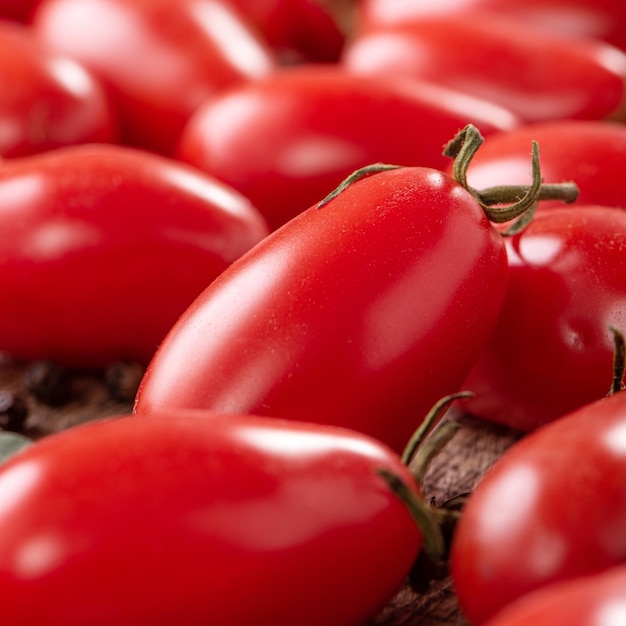 Gros plan de tomates cerises fraîches dans un panier avec des épices sur fond de table en bois.