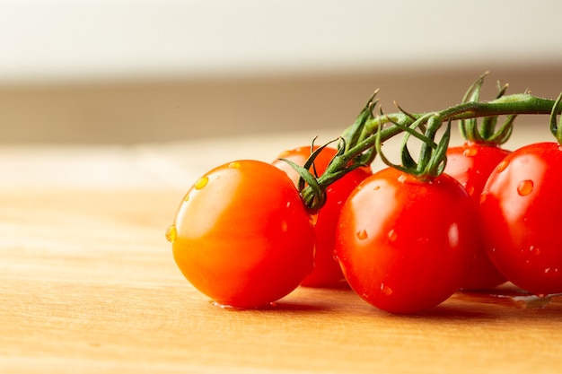 Gros plan sur les tomates cerises rouges fraîches allongées sur la table et savoureuses avec des gouttes d'eau dessus