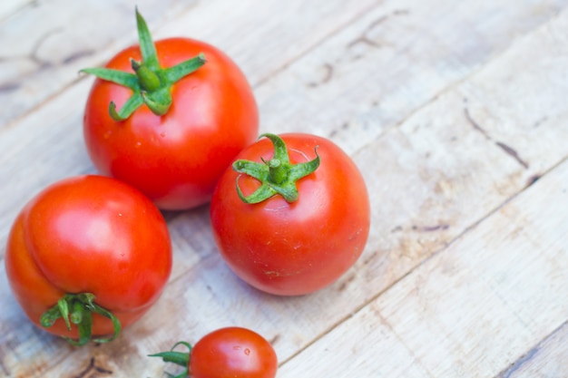 Gros plan de tomates fraîches et mûres sur fond de bois.