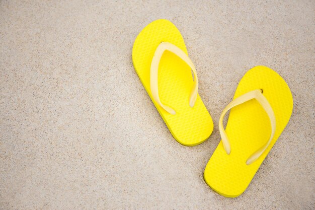 gros plan de tongs jaunes et espace de copie sur la plage de sable