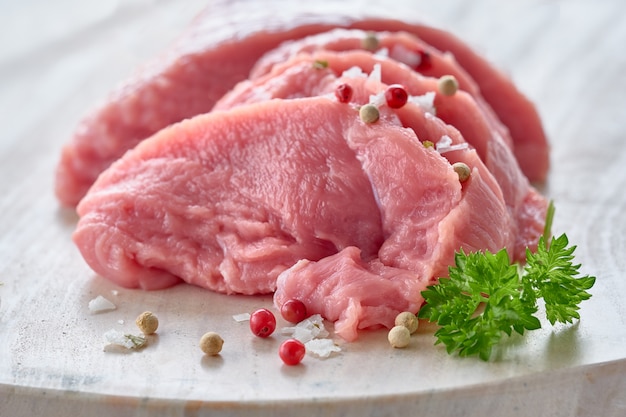 Gros plan sur des tranches de viande de bœuf crue. Filet avec des herbes et des épices sur panneau de pierre.