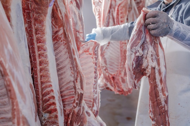 Gros plan sur la transformation de la viande dans l'industrie alimentaire un travailleur coupe le porc cru le concept de produits à base de viande