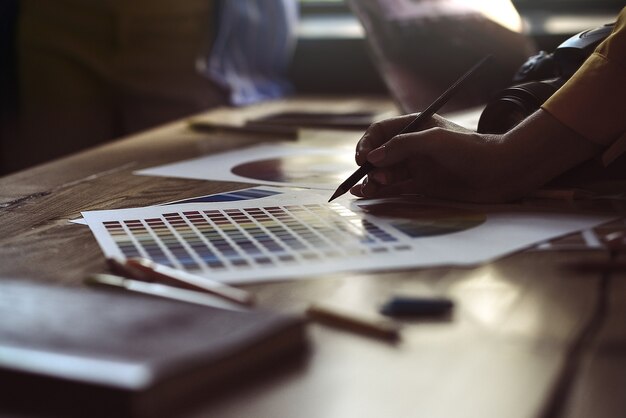 Gros plan sur le travail d'équipe d'architectes d'intérieur avec des plans de construction de maisons sur un bureau, des architectes travaillant avec une palette de plusieurs couleurs pour choisir la meilleure couleur pour la conception.