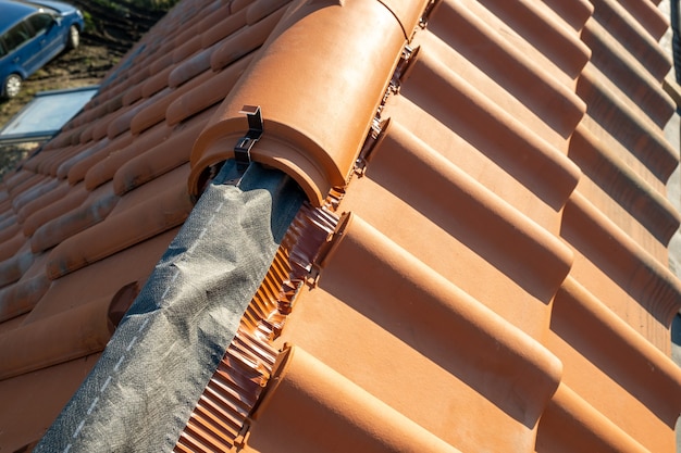 Gros plan de tuiles faîtières en céramique jaune sur le toit d'un immeuble résidentiel en construction.