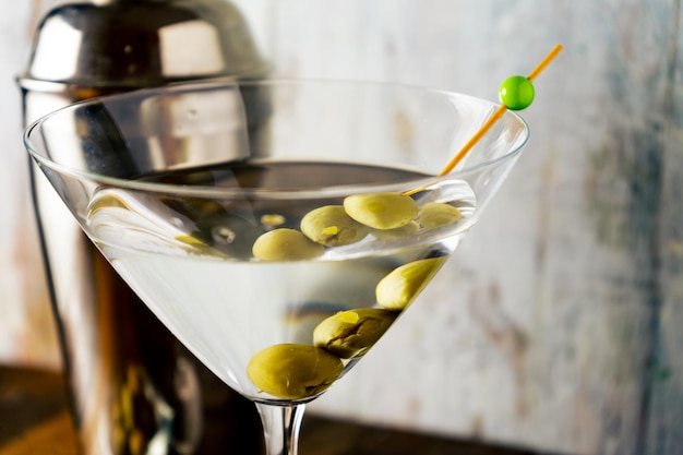 Gros plan d'un verre à martini aux olives sur fond clair.