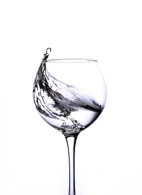 Gros plan sur un verre transparent avec une éclaboussure d'eau sur fond blanc