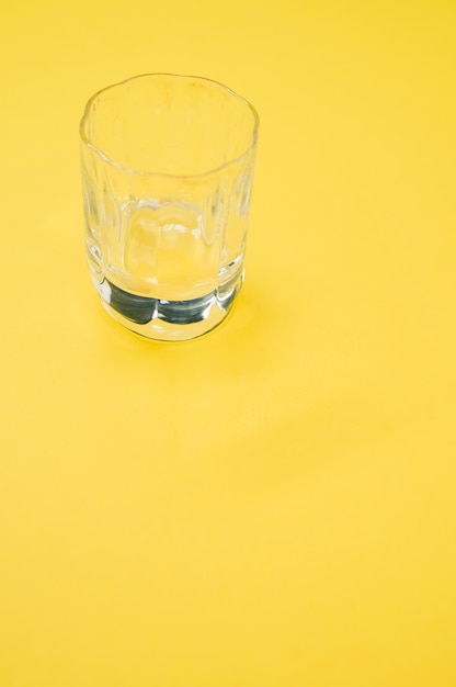 Gros plan d'un verre vide sur un espace de copie de surface jaune