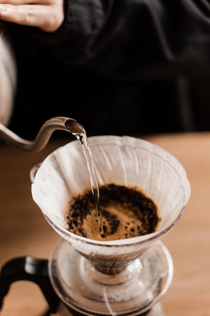 Gros plan versez sur le filtre avec du café moulu dans l'entonnoir au point Infusion de café filtre goutte à goutte Versez sur une méthode alternative de verser de l'eau sur les grains de café torréfiés et moulus contenus dans le filtre