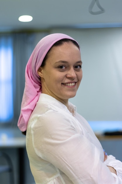 Gros plan vertical d'une femme souriante portant un foulard rose en référence au cancer