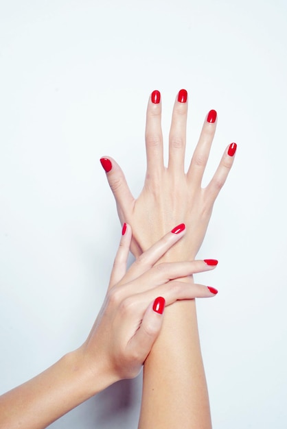 Gros plan vertical tourné de mains féminines avec du vernis à ongles rouge