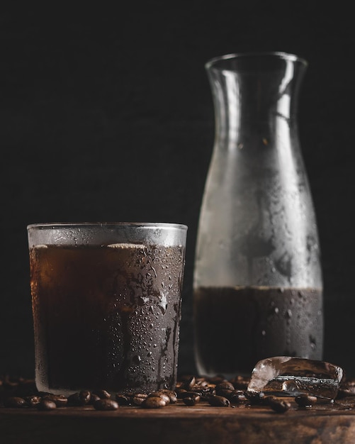 Gros plan vertical d'un verre de café froid avec une bouteille en arrière-plan