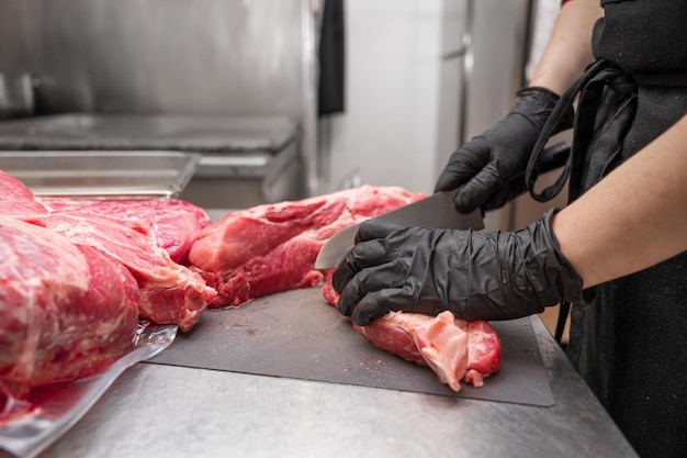 Gros plan sur de la viande crue et une femme boucher coupant de la viande avec un couteau