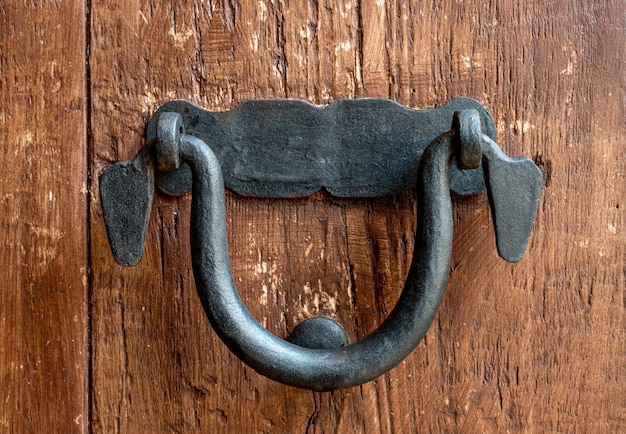 Gros plan d'une vieille poignée de porte noire sur une porte en bois marron