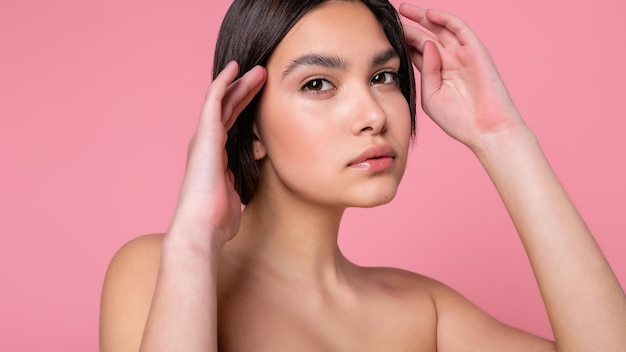 Gros plan visage d'une belle jeune femme avec une peau propre et parfaite Portrait d'un modèle de beauté avec un maquillage nude naturel Spa soins de la peau et bien-être Fond corail pêche rose 169 format panoramique