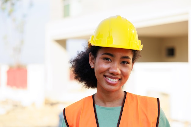 Gros plan visage femme noire portrait femal ingénieur afro-américain travailleur portant un casque de casque jaune travaillant sur un chantier de construction
