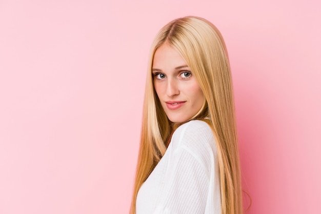 Gros plan visage de jeune femme blonde isolé sur un mur rose