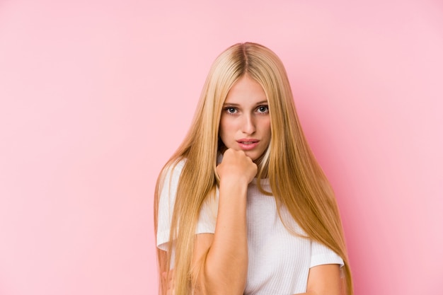 Gros plan visage de jeune femme blonde isolé sur un mur rose