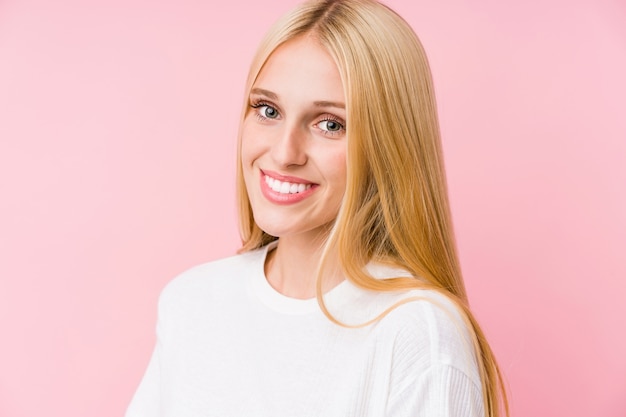 Gros plan visage de jeune femme blonde sur un mur rose