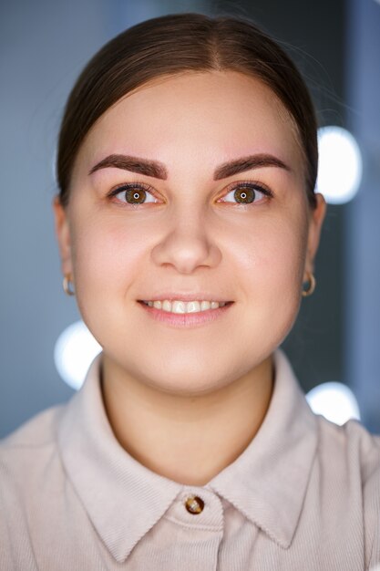 Gros plan sur le visage d'une jeune femme qui vient de se faire tatouer les sourcils de façon permanente.