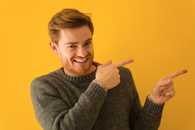 Gros plan visage jeune homme rousse pointant vers le côté avec le doigt