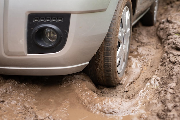 Gros plan d'une voiture coincée dans une mare de boue à la campagne Chemin de terre après les pluies de boue sur la route