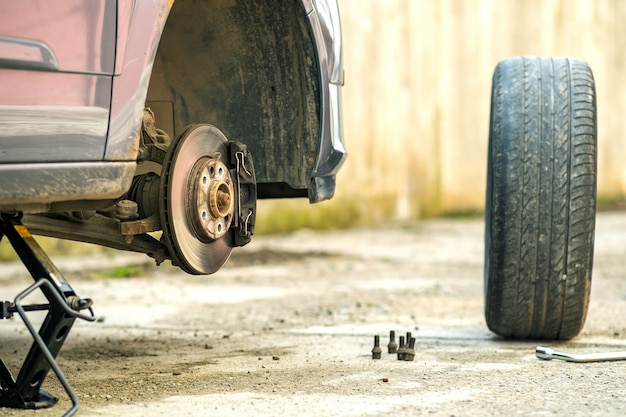 Gros plan d'une voiture levée sur cric en cours de remplacement de nouveaux pneus de roue. Panne d'un véhicule dans une rue.