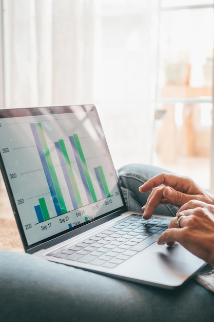 Gros plan vue arrière jeune femme utilisant un ordinateur portable et une calculatrice travaillant sur un projet vérifiant des documents financiers assis à table à la maison regardant un écran d'ordinateur avec des diagrammes calculant des facturesxA