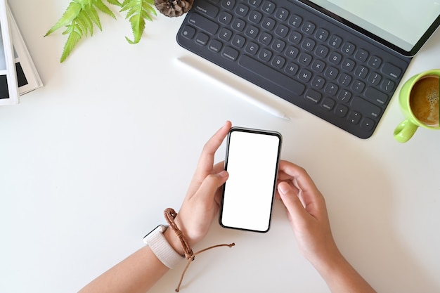 Gros plan et vue de dessus de la femme à l&#39;aide de smartphone mobile sur le bureau blanc