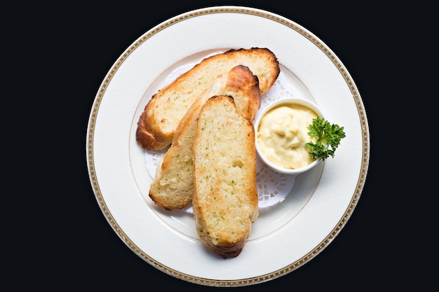 Photo gros plan vue de dessus pain à l'ail cuit en tranches avec de la mayonnaise et du persil dans une assiette blanche