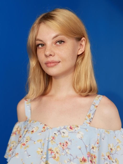 Gros plan vue de face d'une adorable jeune femme blonde aux cheveux blonds regardant la caméra isolée sur fond bleu