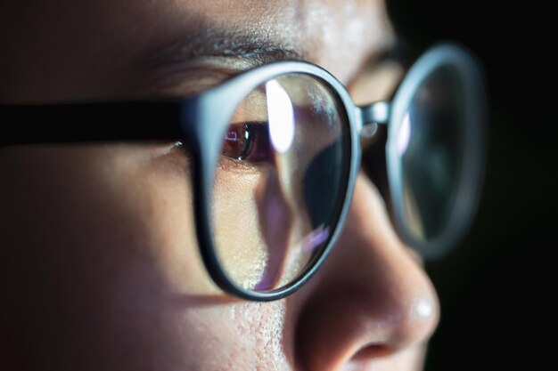 Gros plan d'yeux de femme dans des verres reflétant un écran bleu d'ordinateur en état de marche