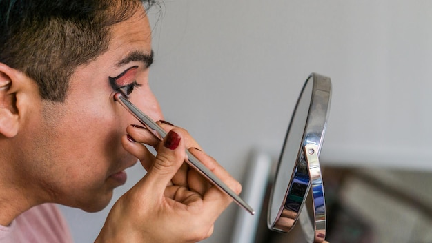 Gros plan sur les yeux d'un homme à l'aide d'un miroir et d'un eye-liner. Mode de vie.