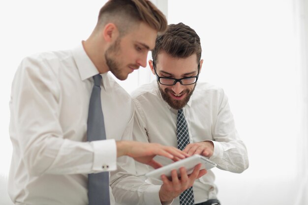 Gros plandeux employés regardant l'écran de la tablette numériqueles gens et la technologie