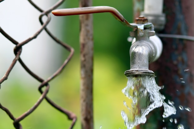 Gros robinet en laiton grunge sur fond vert bokeh. Concept de pénurie d'eau et de jour de la terre.