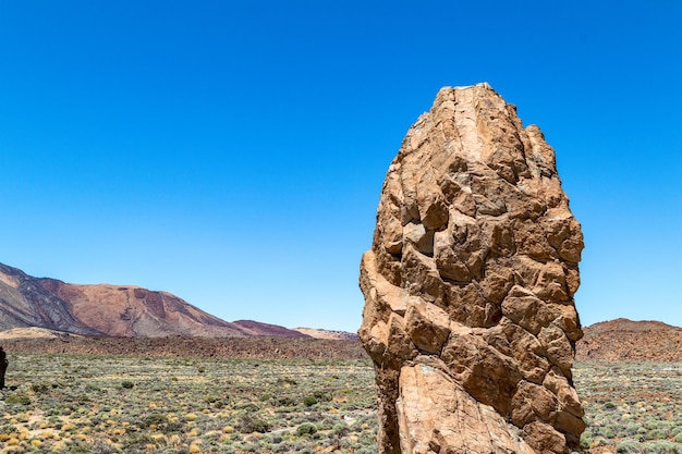 Un gros rocher dans le désert avec un fond de ciel bleu