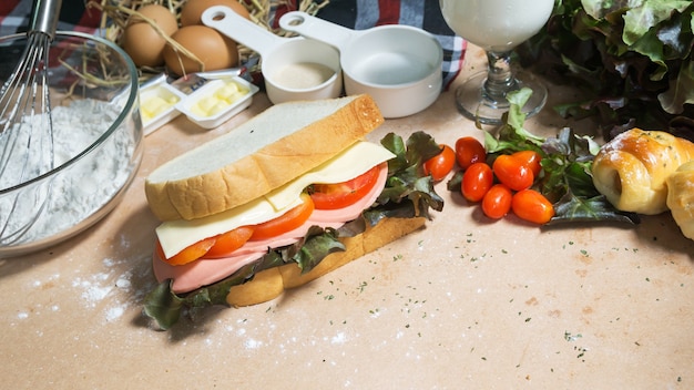 gros sandwich avec jambon, fromage et légumes sur bois