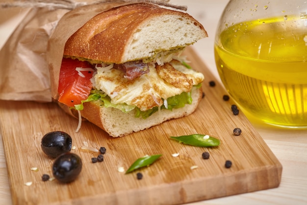 Gros sandwich sur une planche à découper en bois avec des ingrédients