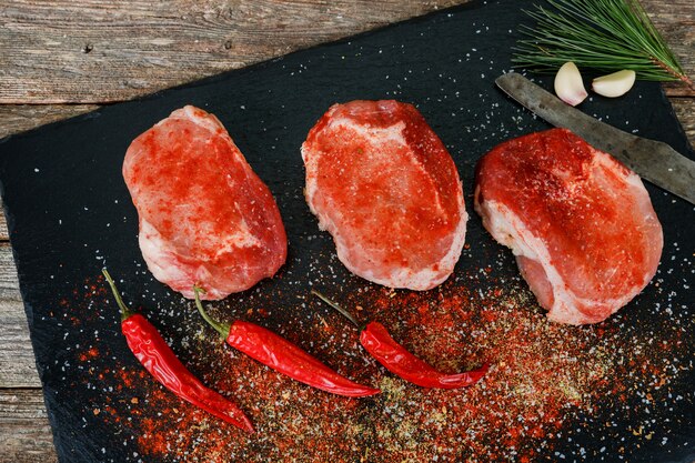 Gros steak au romarin et épices sur fond rustique foncé.